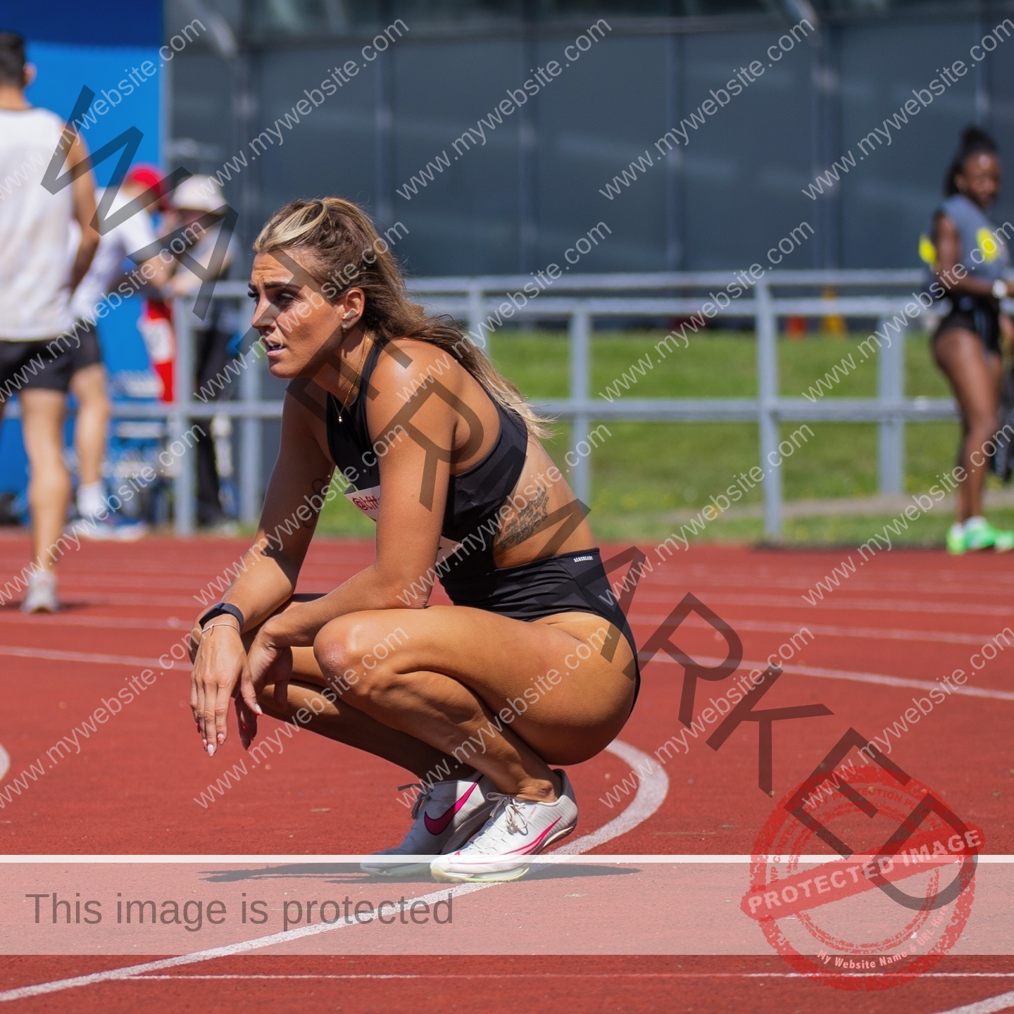 charlotte-wingfield-malta-charlottewingfield.oly-03949 Charlotte Wingfield, track athlete from Malta, in black sportswear squats on a red track, focused and tired, with others behind her.