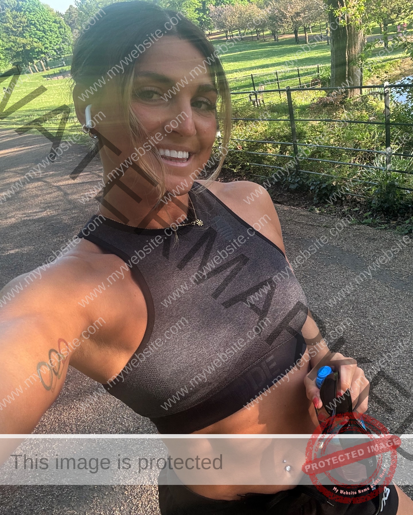 charlotte-wingfield-malta-charlottewingfield.oly-04002 Charlotte Wingfield, track athlete from Malta, smiles in a selfie on a park path, in athletic wear with Olympic rings tattoo visible.