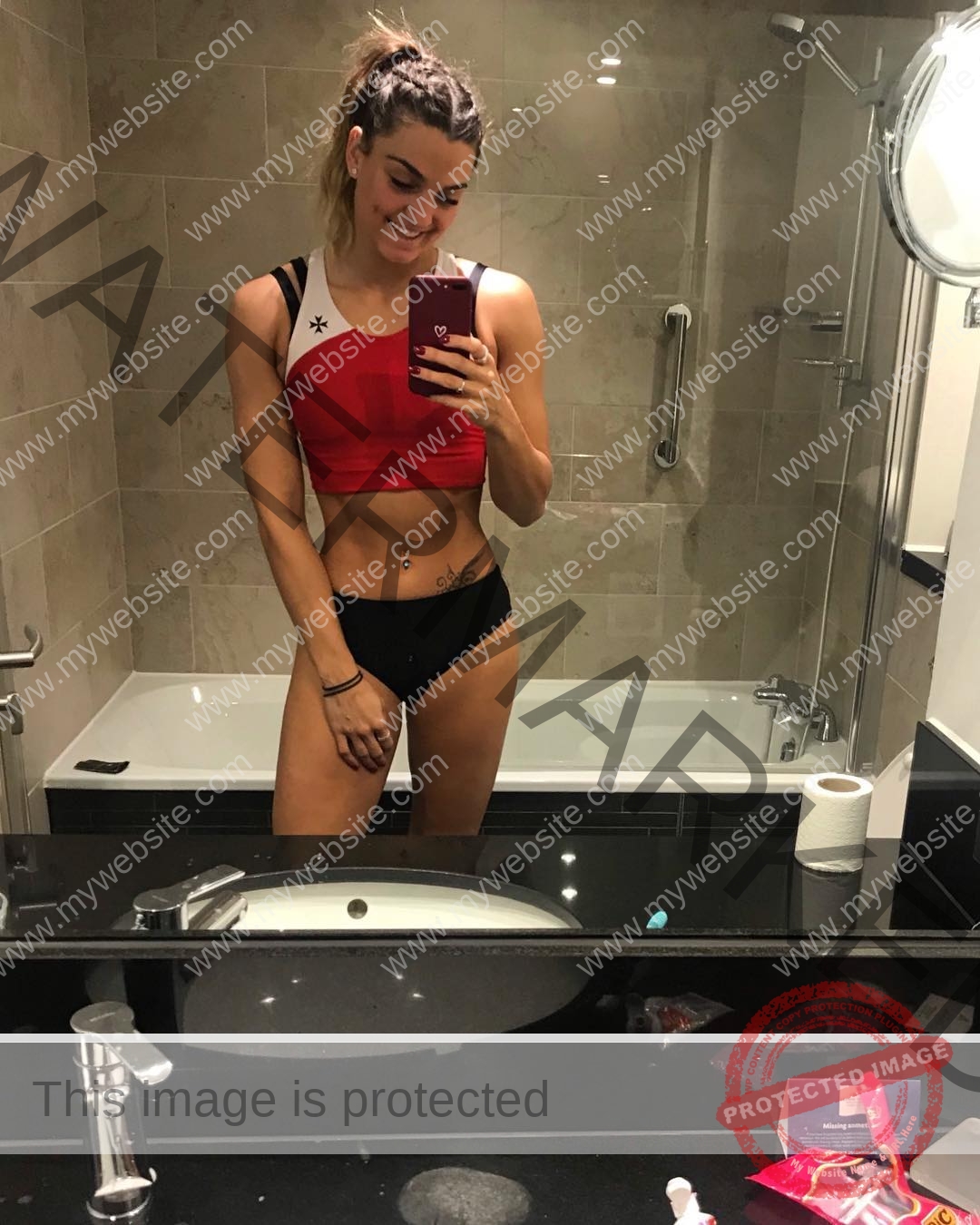 charlotte-wingfield-malta-charlottewingfield.oly-04071 Charlotte Wingfield, track athlete from Malta, in a red sports bra and black underwear, smiles taking a bathroom mirror selfie.
