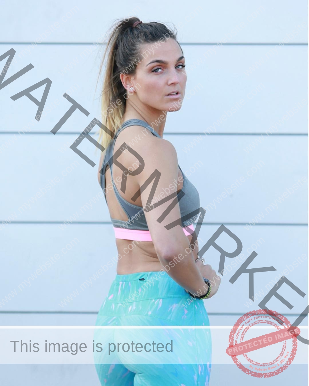 charlotte-wingfield-malta-charlottewingfield.oly-04072 Charlotte Wingfield, track athlete from Malta, stands sideways in a grey sports bra and blue leggings, looking back at the camera.