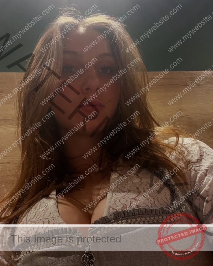 Chiara Wildner, track athlete from Germany, with long light brown hair, in a white lace top, poses by a wooden background.