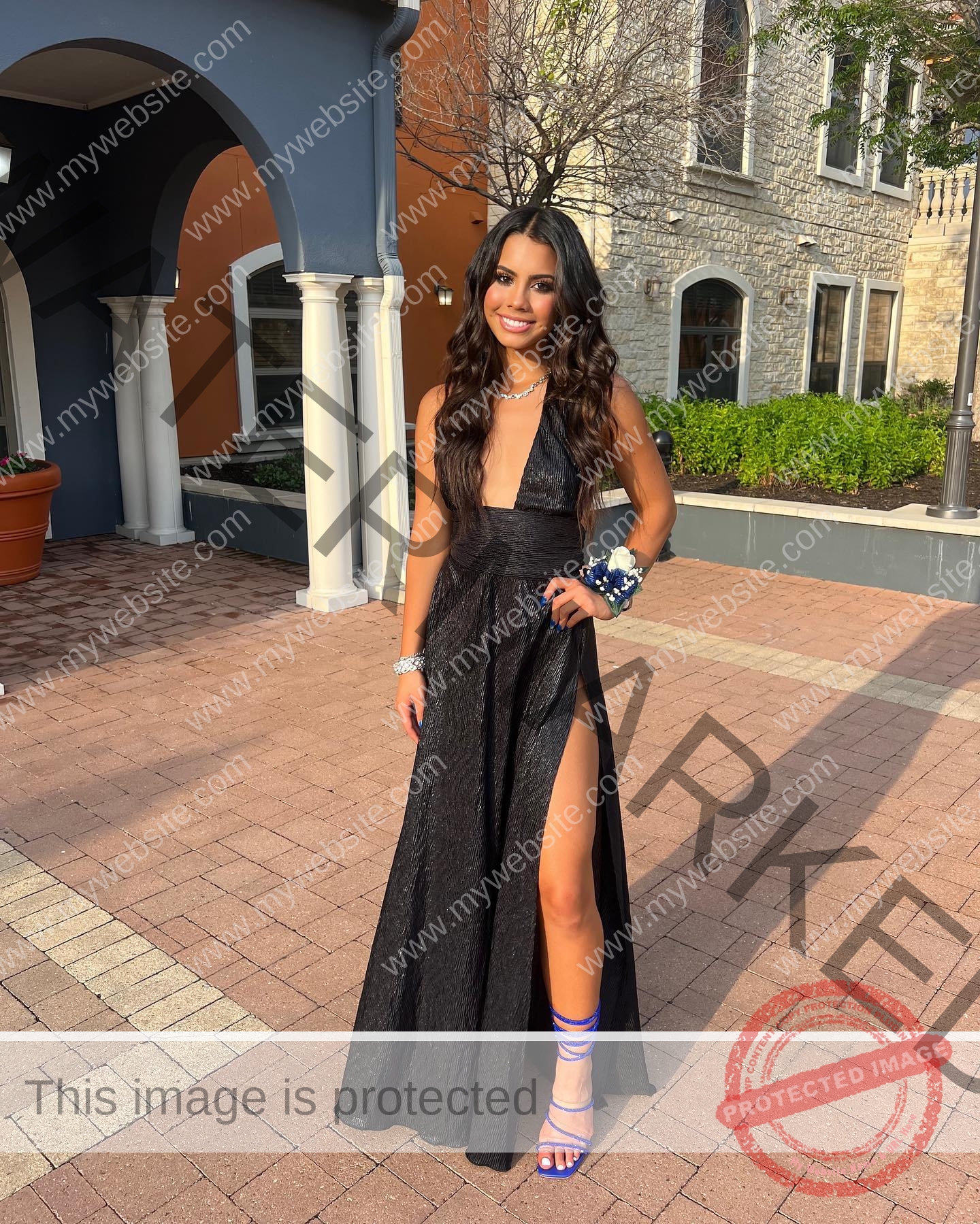 ciandra-carrico-trinity-ciandracarrico-4209 Ciandra Carrico, track athlete from Trinity, stands smiling outside in a black gown with blue heels and a corsage by brick arches.