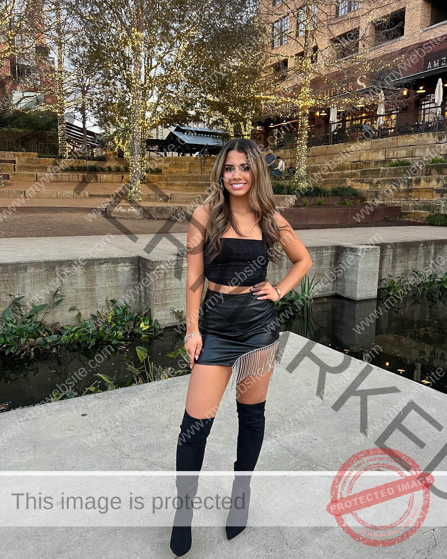 ciandra-carrico-trinity-ciandracarrico-4261 Ciandra Carrico, track athlete from Trinity, stands outdoors near water in a black crop top, fringed mini skirt, and knee-high boots.