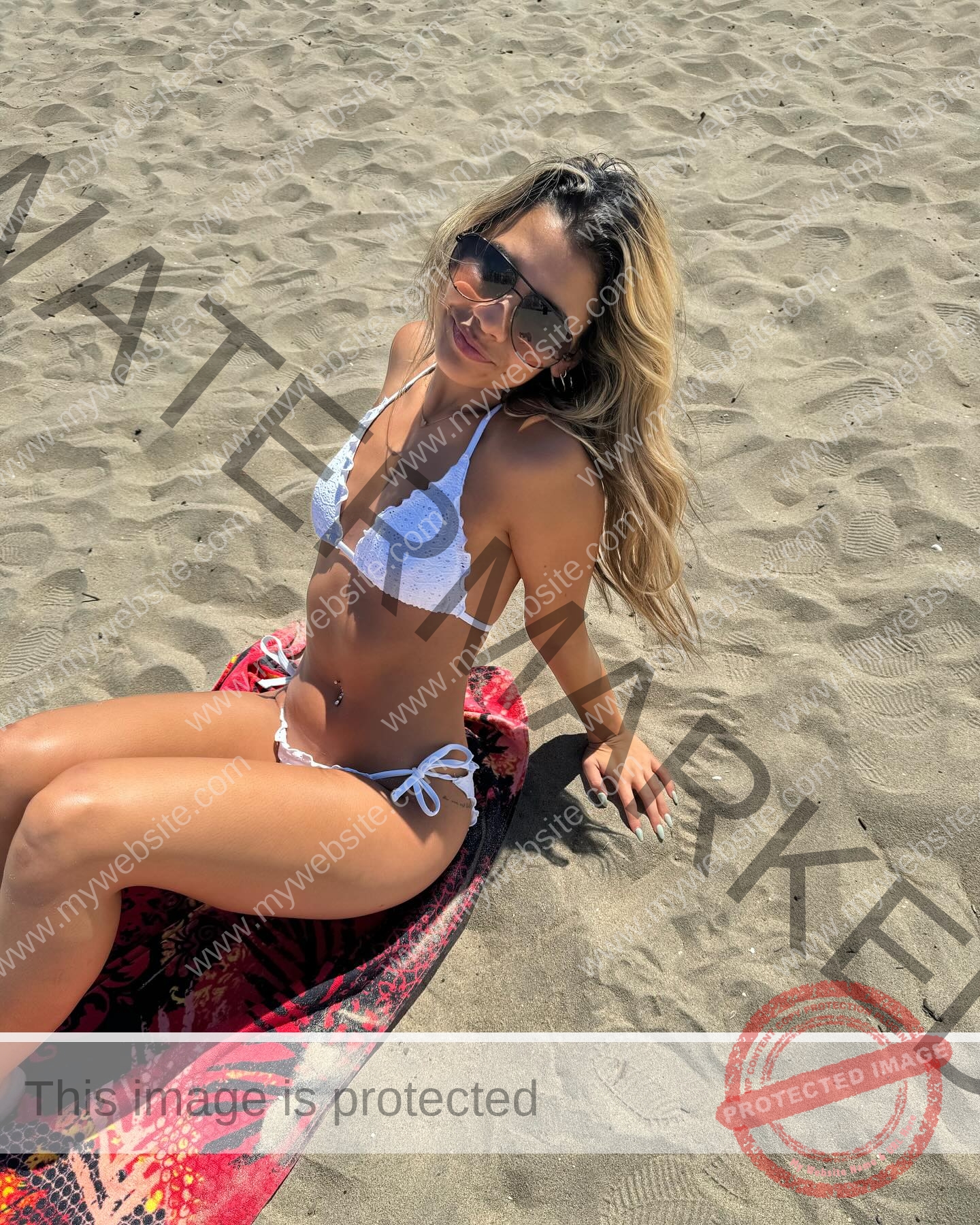 ciandra-carrico-trinity-ciandracarrico-4287 Ciandra Carrico, track athlete from Trinity, in a white bikini and sunglasses sits on a surfboard on the sandy beach, looking up.