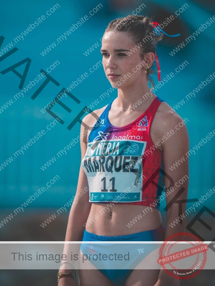Claudia Marquez, track athlete from Jacksonville State, wears a red and blue uniform and bib outdoors, looking focused.