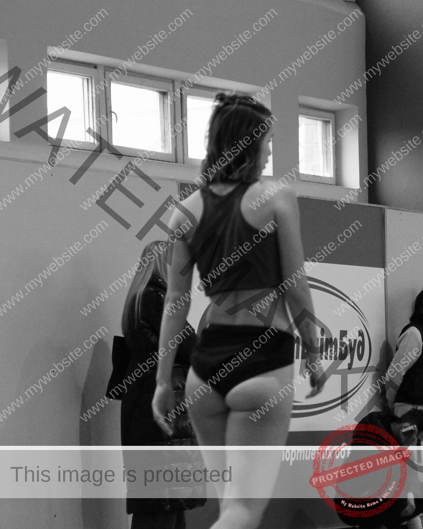 daria-polyanskaya-ukraine-polyanska.ya-x-08629 Daria-Polyanskaya, track athlete from Ukraine, stands in athletic wear indoors, back to camera; others and Cyrillic sign in view.