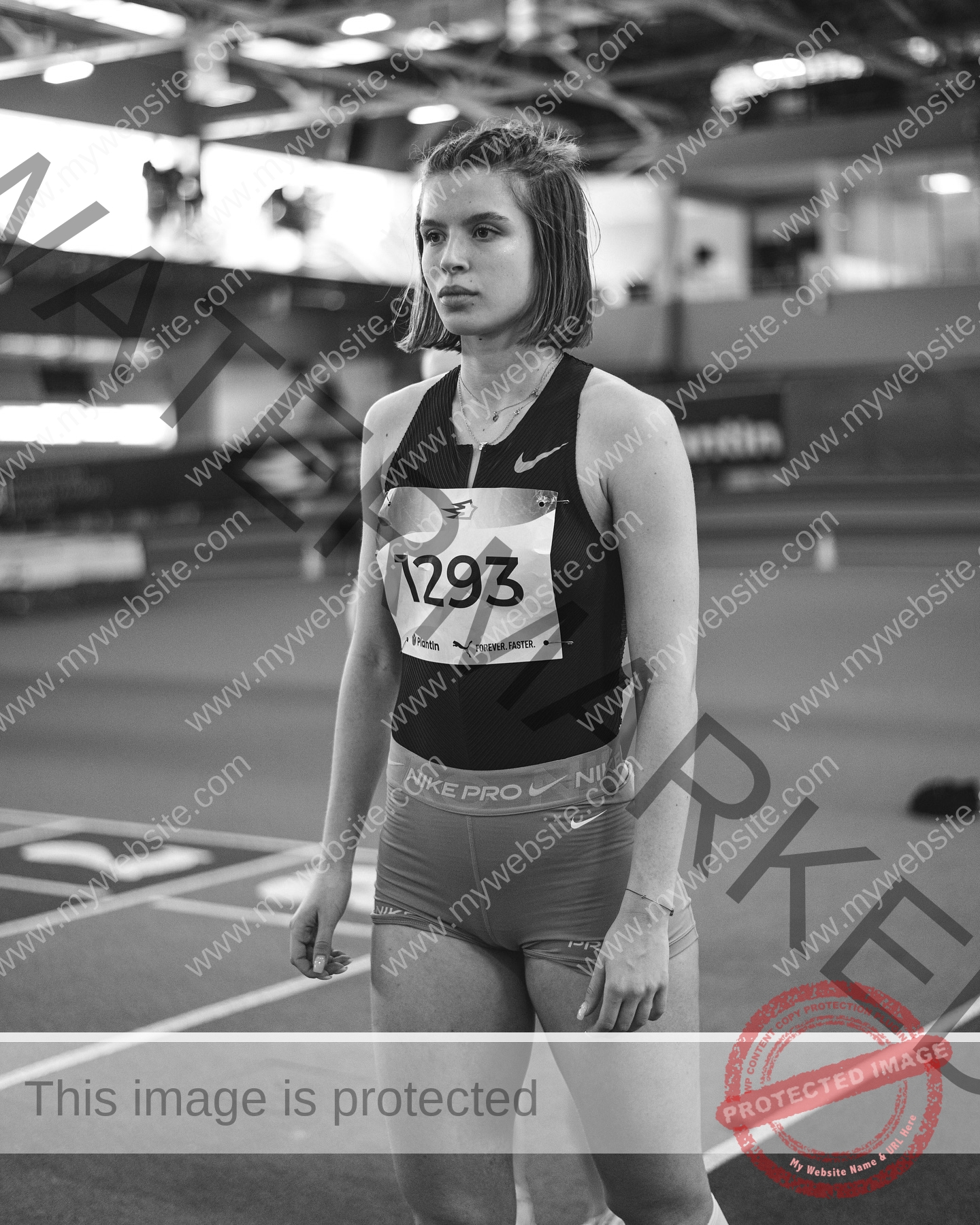 daria-polyanskaya-ukraine-polyanska.ya-x-08655 Daria-Polyanskaya, track athlete from Ukraine, stands on an indoor track in Nike Pro gear and bib 1293, looking focused.