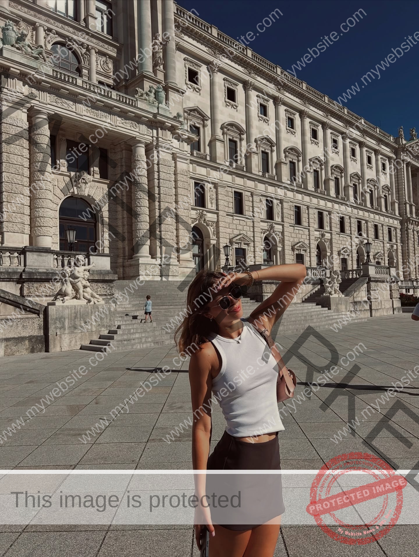 daria-polyanskaya-ukraine-polyanska.ya-x-08756 Daria-Polyanskaya, track athlete from Ukraine, in sunglasses and summer attire stands outside a grand building on a sunny day.
