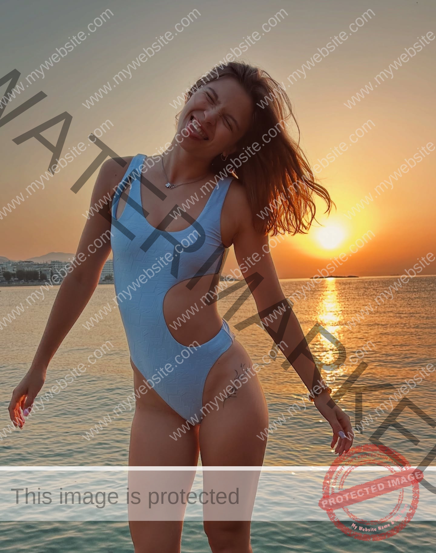 daria-polyanskaya-ukraine-polyanska.ya-x-08771 Daria-Polyanskaya, track athlete from Ukraine, in a light blue swimsuit smiles playfully on a beach at sunset by the calm sea.