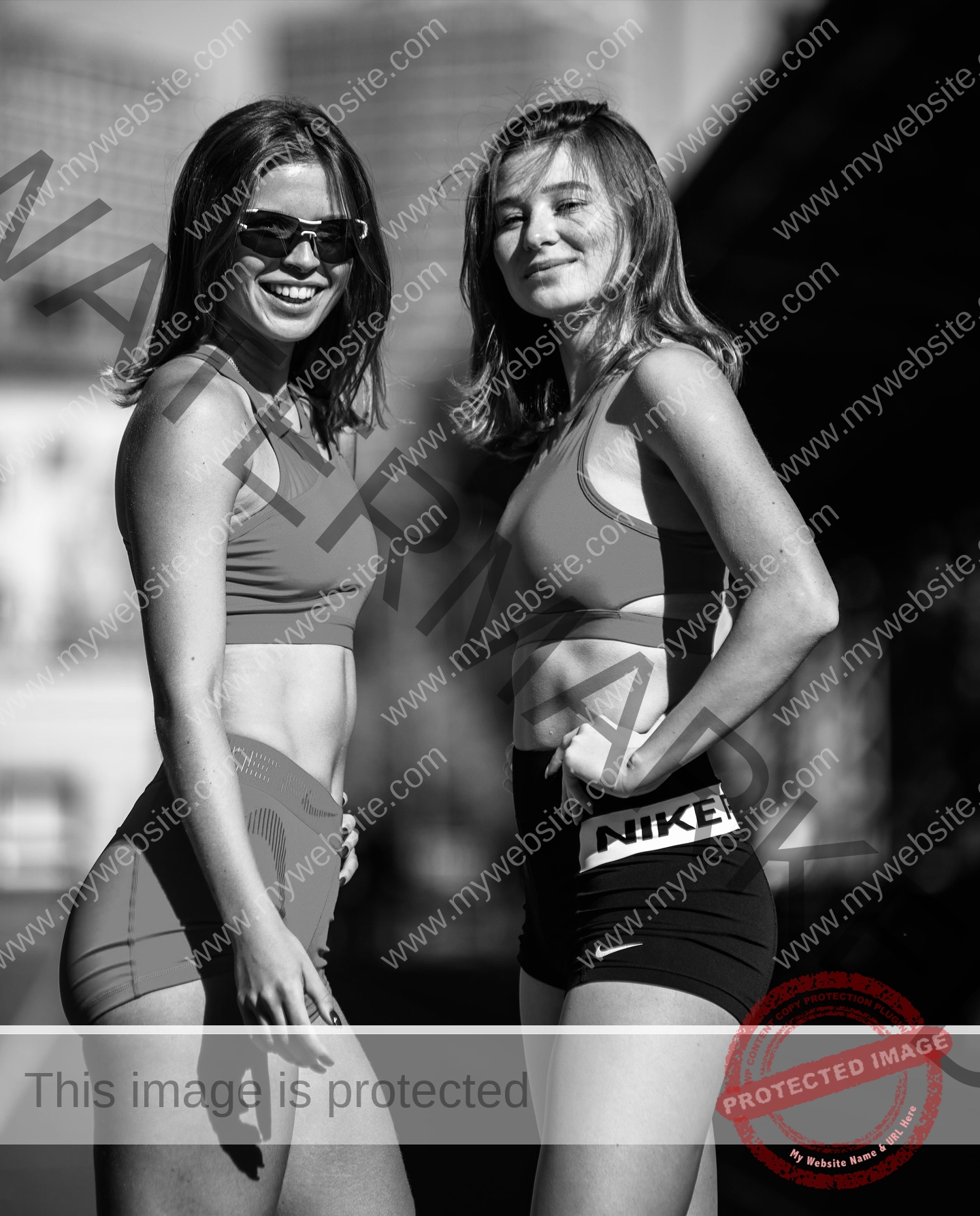 daria-polyanskaya-ukraine-polyanska.ya-x-08789 Daria-Polyanskaya, track athlete from Ukraine, two young women in sports bras and shorts outdoors smiling, sunlight on faces.
