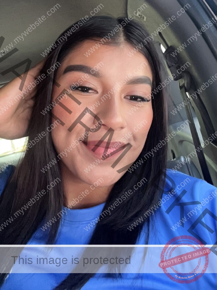 Debora Viviana Mendez, track athlete from Guatemala, smiles in a car with straight dark hair, blue shirt, softly lit by sunlight.