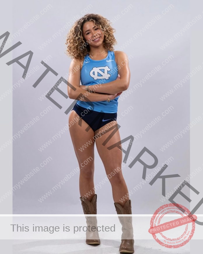 Delea Martins Delea Martins, a UNC track and field athlete with curly hair, smiles arms crossed in a blue tank, shorts, and cowboy boots.