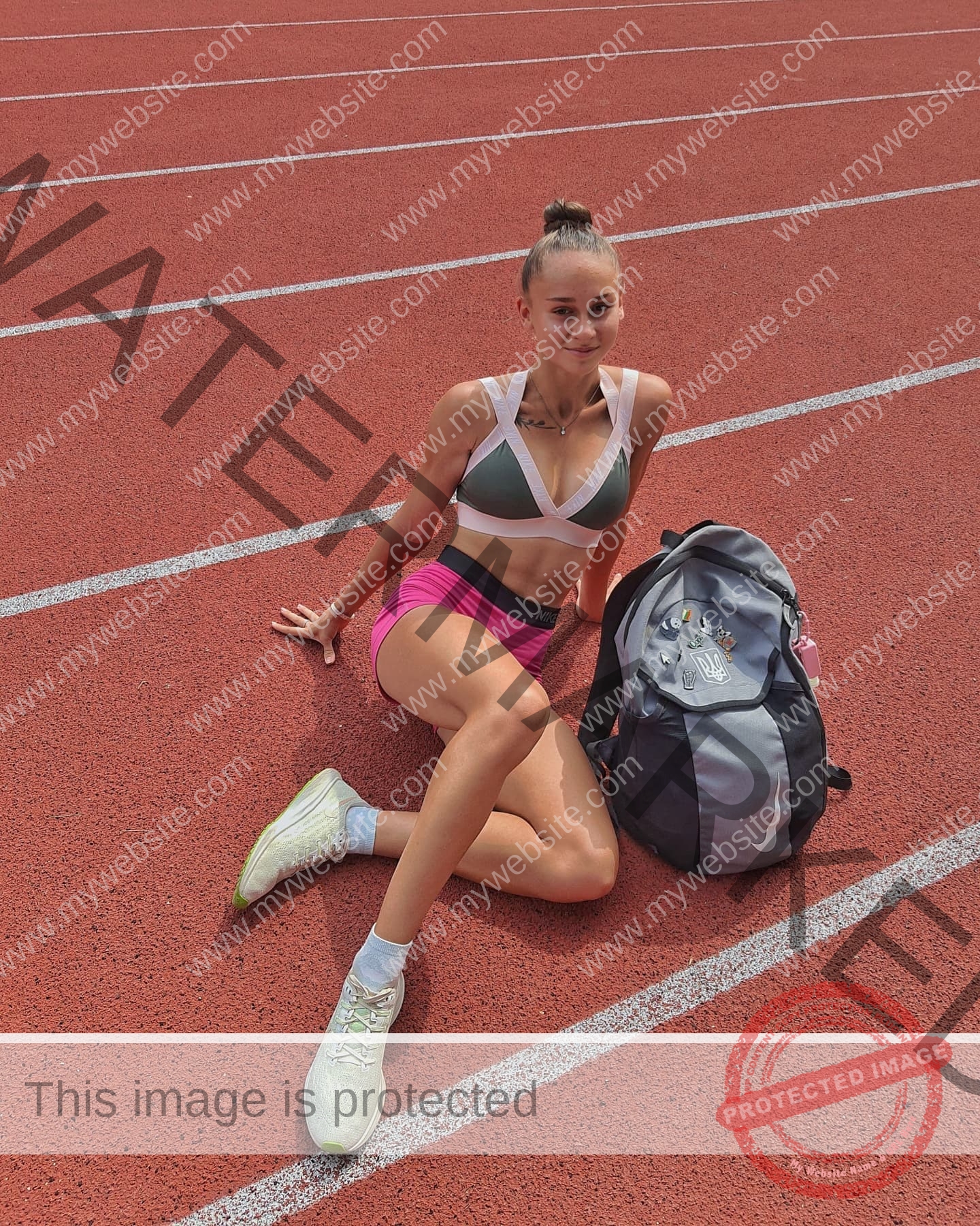 diana-honcharenka-ukraine-goncharenko_43-09539 Diana Honcharenka, track athlete from Ukraine, in athletic wear sits on a red track by a sports bag, one knee bent, lines behind.