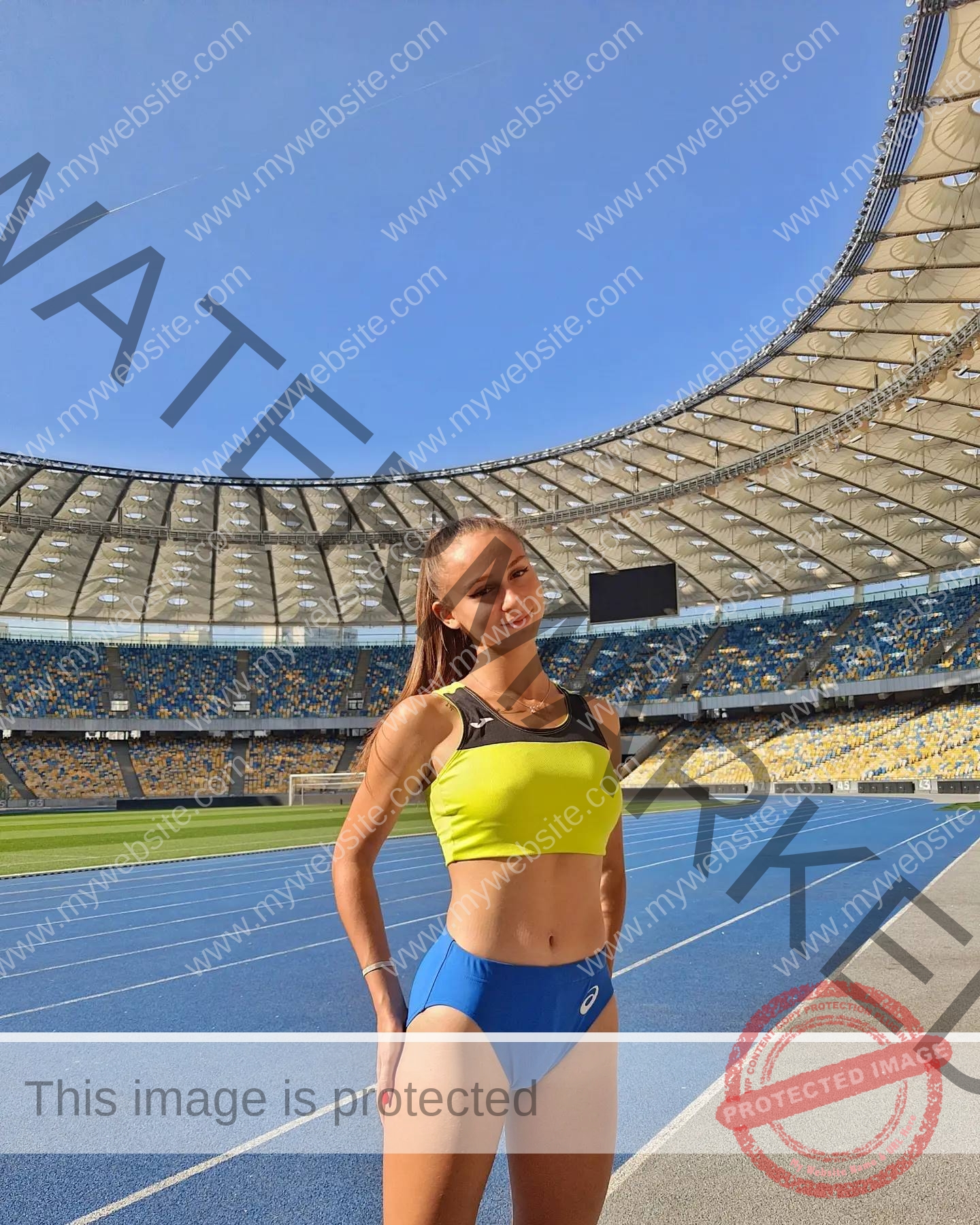 diana-honcharenka-ukraine-goncharenko_43-09557 Diana Honcharenka, track athlete from Ukraine, in a yellow sports bra and blue shorts stands smiling on a sunny stadium track.
