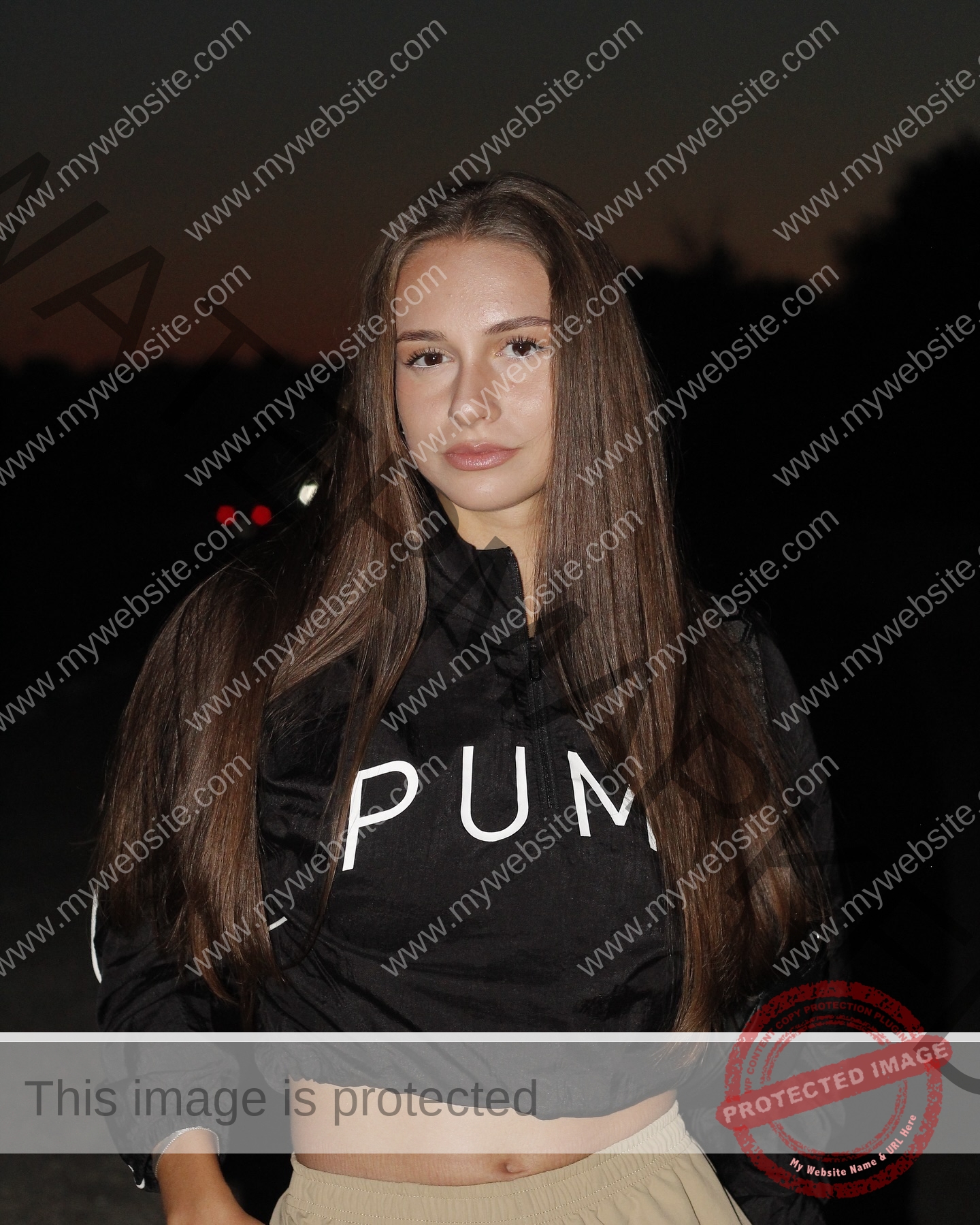 diana-honcharenka-ukraine-goncharenko_43-09844 Diana Honcharenka, track athlete from Ukraine, stands at dusk in a black PUMA jacket and beige pants; dark trees silhouette behind.