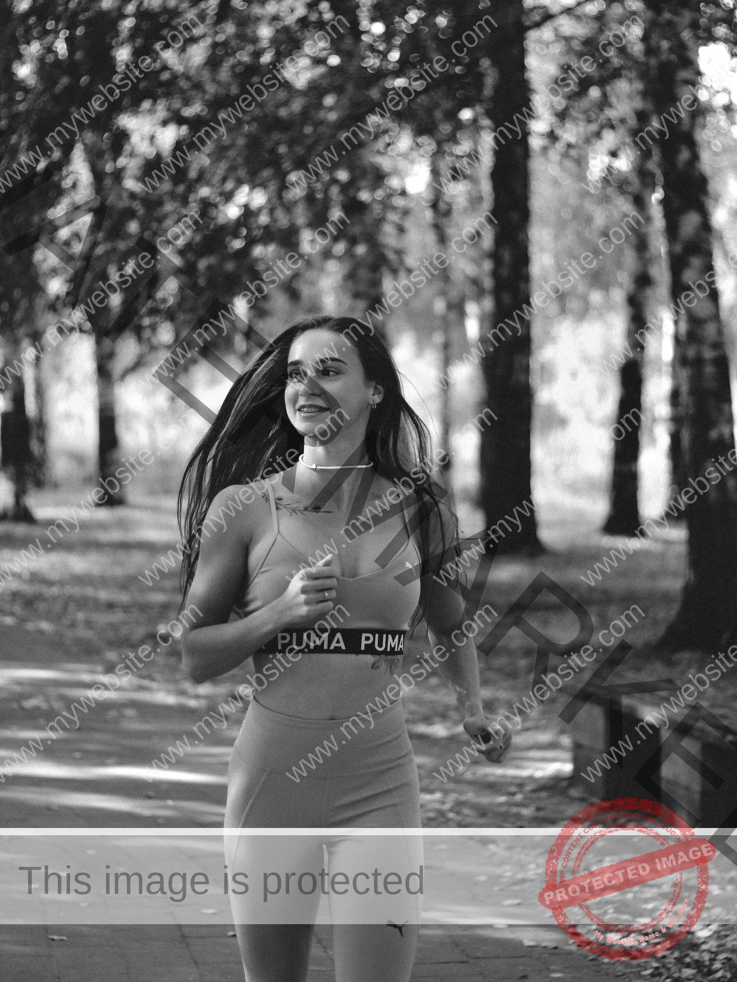 diana-honcharenka-ukraine-goncharenko_43-09949 Diana Honcharenka, track athlete from Ukraine, jogs in athletic wear on a tree-lined park path, smiling in a black and white photo.
