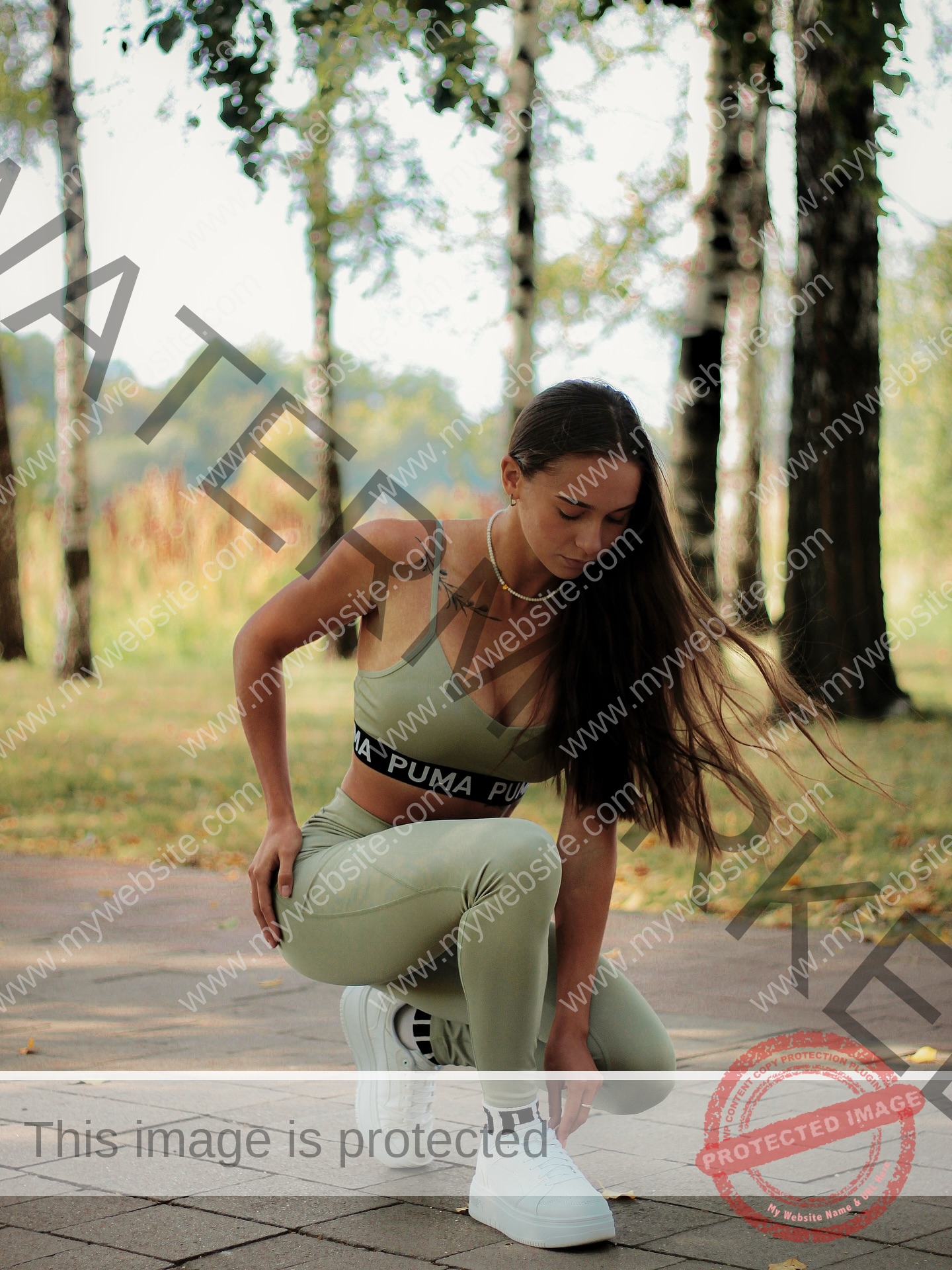 diana-honcharenka-ukraine-goncharenko_43-09951 Diana Honcharenka, track athlete from Ukraine, in green athletic wear kneels on a path outdoors among trees, adjusting her shoe.