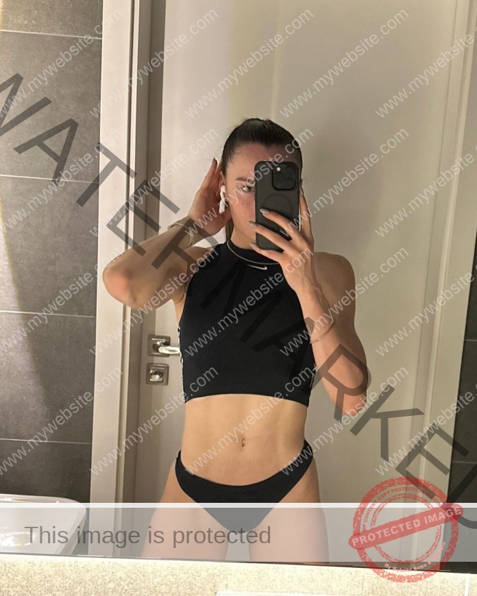 Iryna Butenko A woman in a black crop top and black underwear takes a mirror selfie, phone up, channeling Iryna Butenko’s confident style.
