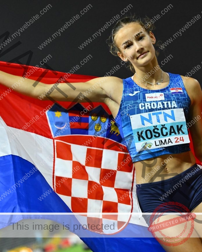 Jana Koscak A female track and field athlete, Jana Koscak, smiles holding a Croatian flag. She wears blue sports gear; background blurred.
