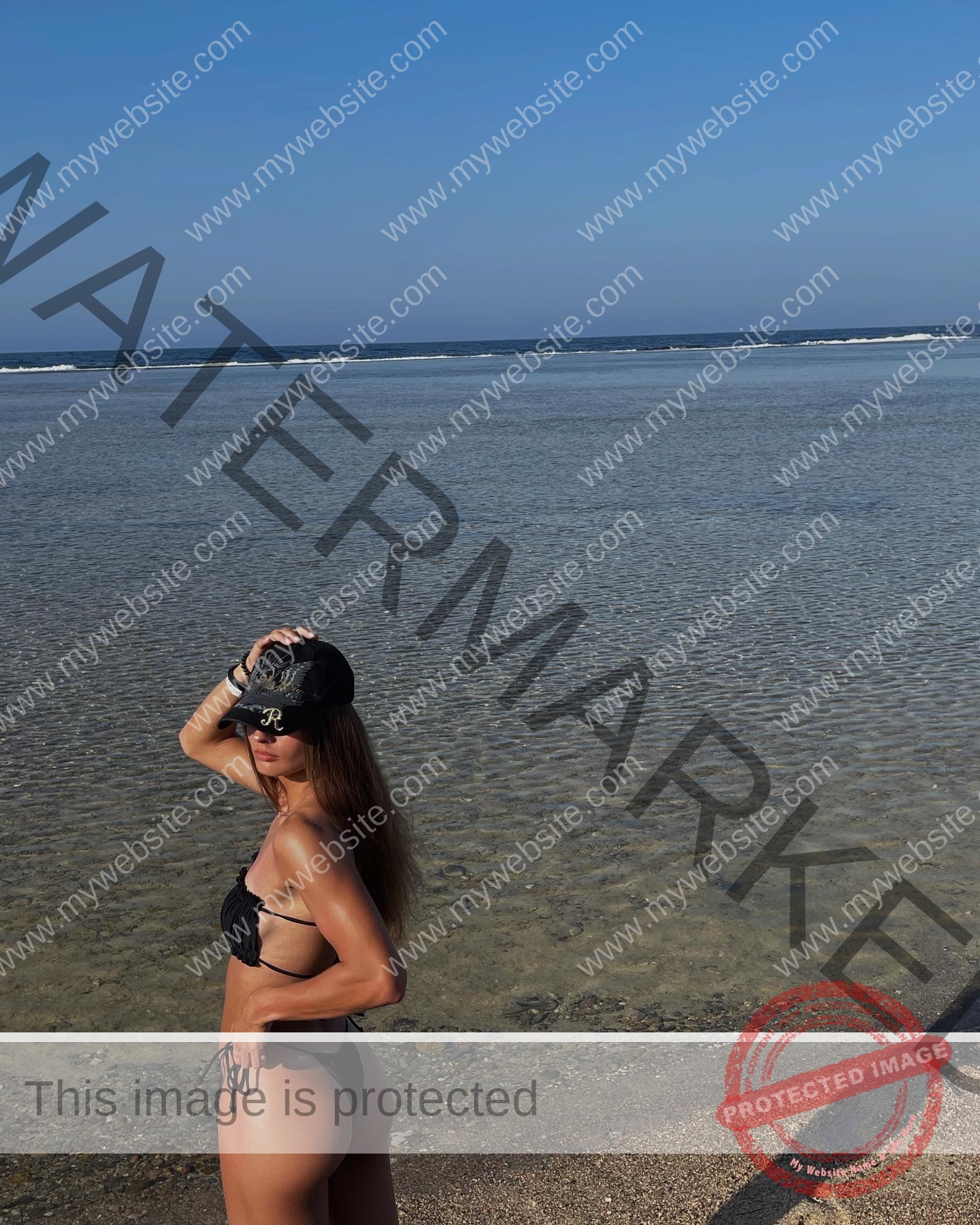 karolina-manasova-czechia-karolina_manasova-332 Karolina Manasova Karolina Manasova, a Czech track and field athlete, poses in a black bikini and cap on a sunny beach, looking confident.