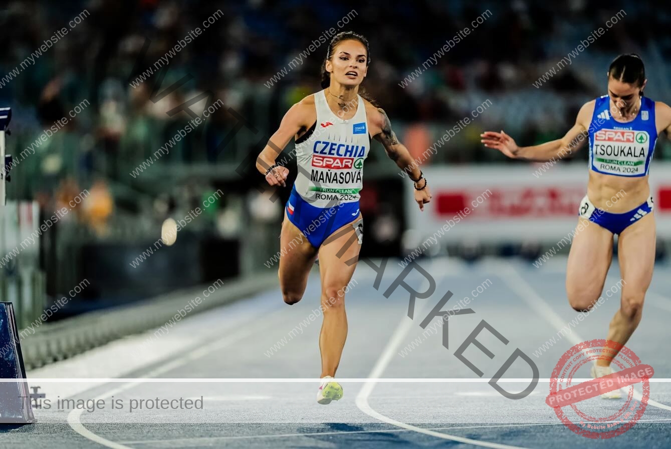 karolina-manasova-czechia-karolina_manasova-351 Karolina Manasova Two female track and field athletes sprint toward the finish, with Karolina Manasova in blue shorts and a white top ahead.