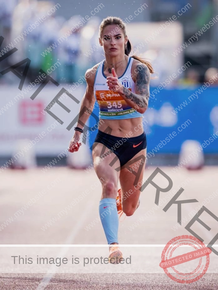 Karolina Manasova Karolina Manasova sprints intensely on the track, focused ahead, one arm forward. Spectators and banners blur behind.