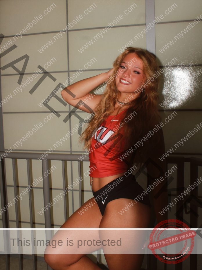 Kennedy Coradini Kennedy Coradini, a young woman with long wavy hair, smiles on an indoor balcony in a red crop top and black shorts.