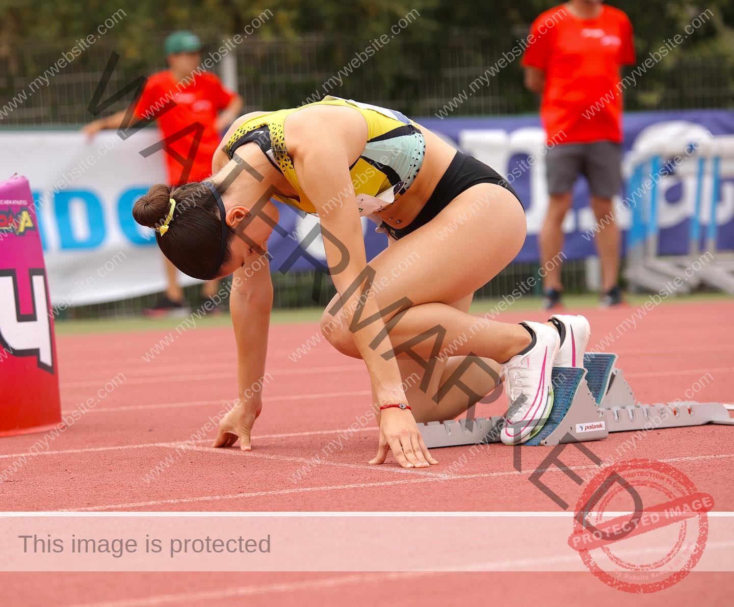 laura-castillo-spain-laura_c.i_-3271 Laura Castillo Laura Castillo, a Spanish female track athlete, readies for a sprint at the starting line; officials in red shirts behind her.