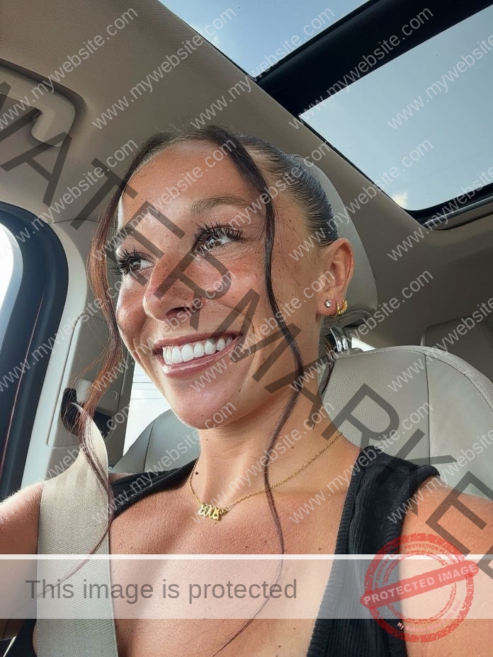 Maggie O'Malley Maggie O'Malley, a GVSU track athlete with brown hair and freckles, smiles in a car. Sunlight shines on her face.