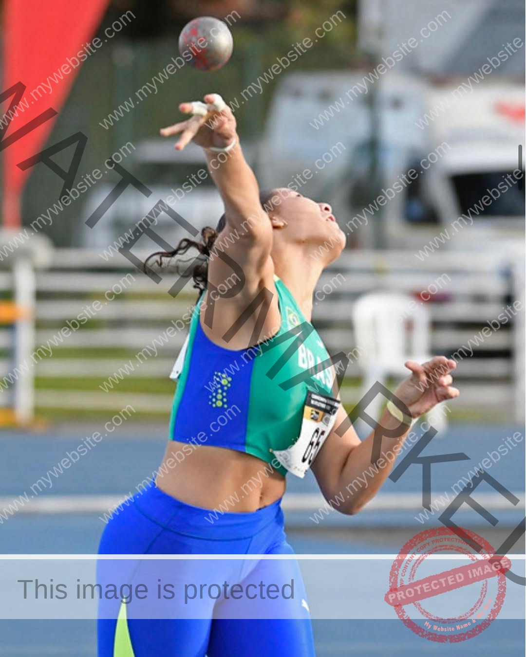 maria-eduarda-dantas-brazil_dudinha_23-1645 Maria Eduarda Dantas, discus thrower from Brazil, in a blue and green Brasil uniform throws a shot put with arm extended mid-air.