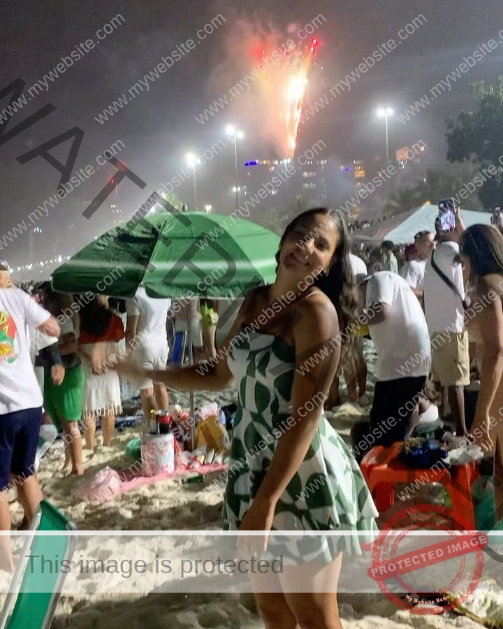 maria-eduarda-dantas-brazil_dudinha_23-1647 Maria Eduarda Dantas, discus thrower from Brazil, smiles in a green and white dress on a crowded beach at night under fireworks.