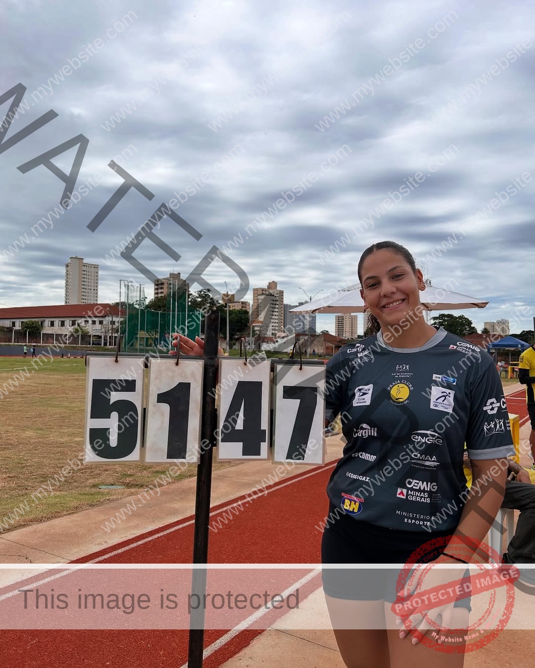 maria-eduarda-dantas-brazil_dudinha_23-1654 Maria Eduarda Dantas, discus thrower from Brazil, stands on a track, smiling and pointing at a scoreboard reading 5147.