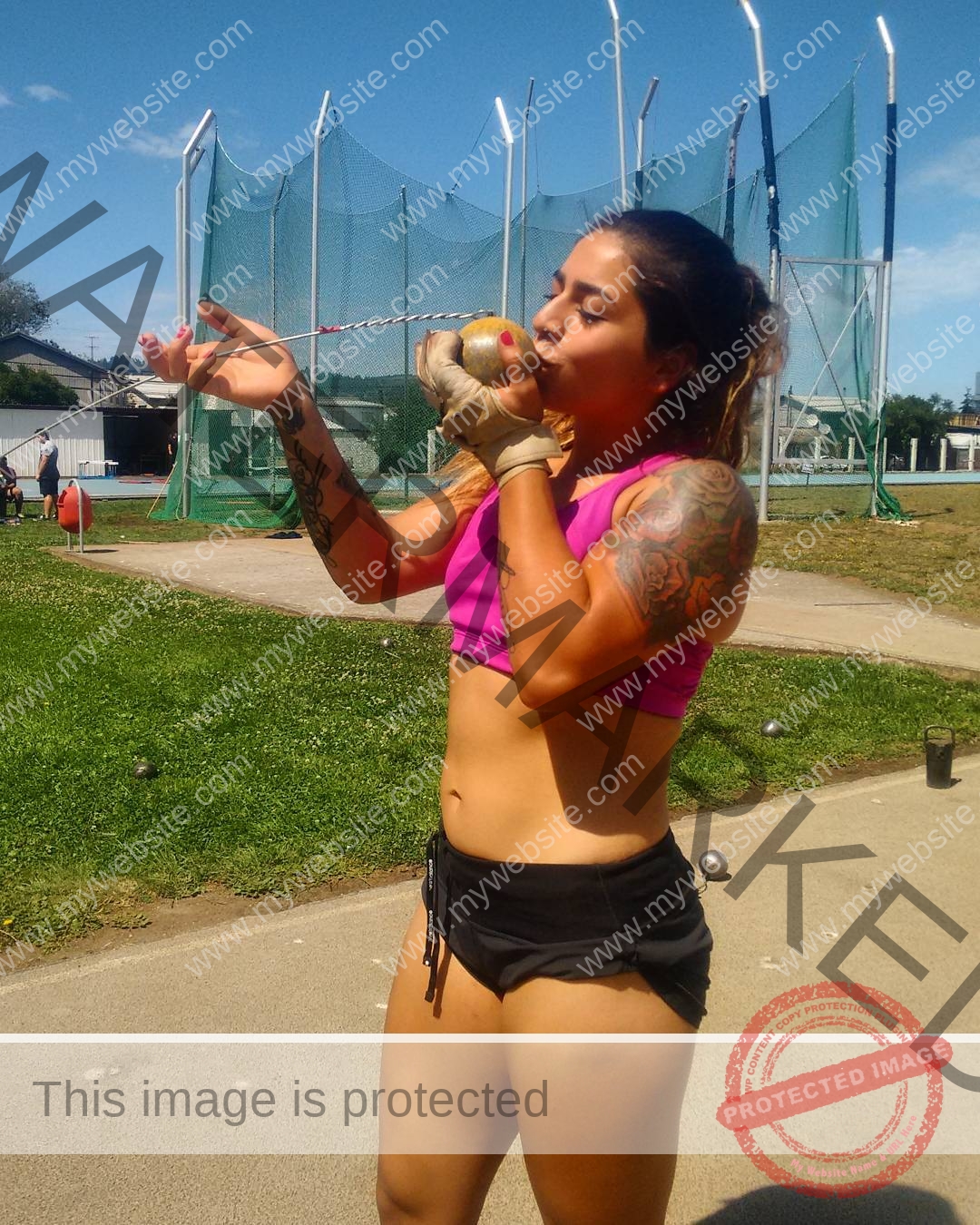 mariana walker-childe-marianawalker_-1688 Mariana Walker, hammer thrower from Chile, kisses a shot put before throwing outdoors on a sunny day near a practice cage and grass.