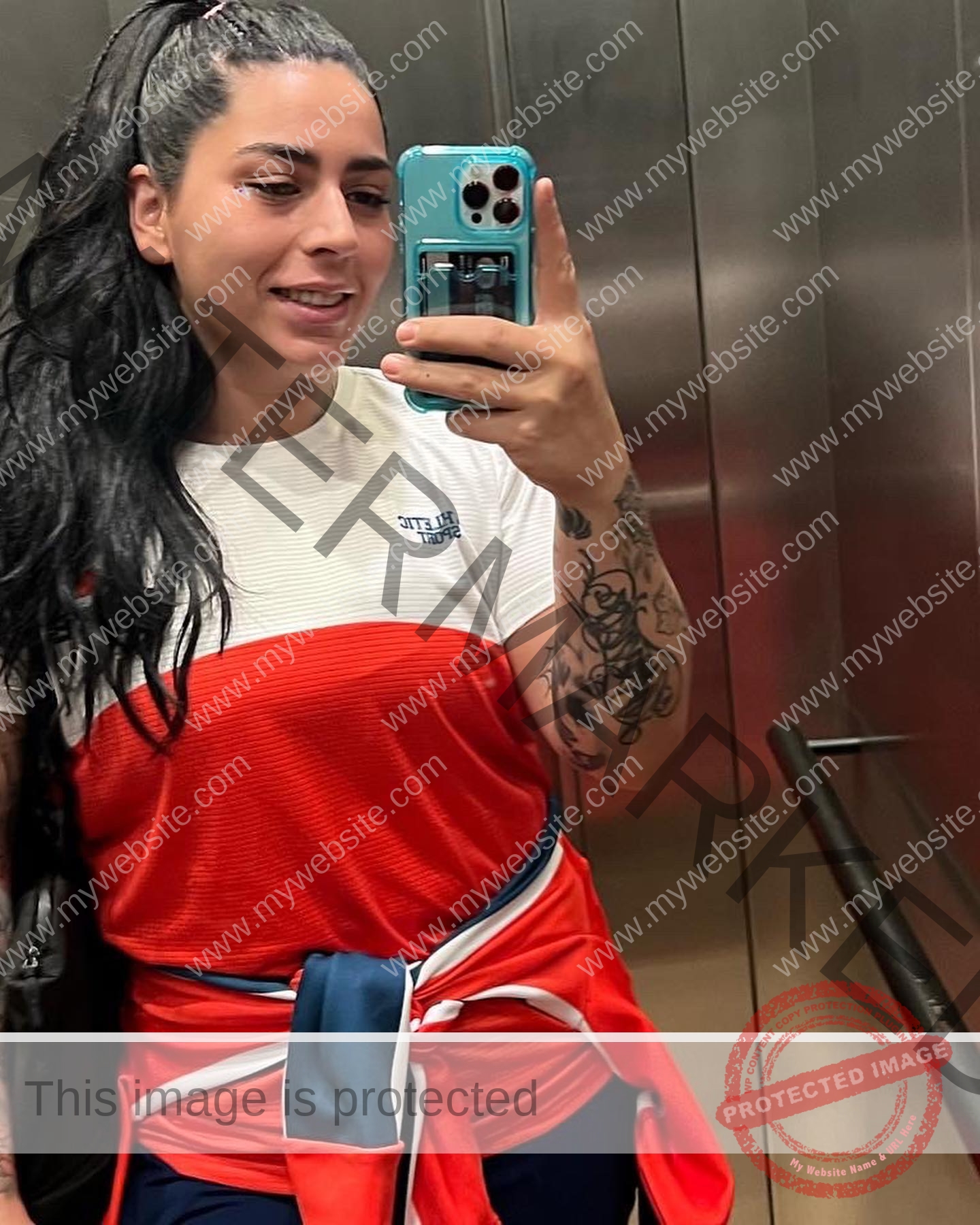mariana walker-childe-marianawalker_-1746 Mariana Walker, hammer thrower from Chile, takes a mirror selfie in an elevator, red, white & navy shirt, tattoos on arm.