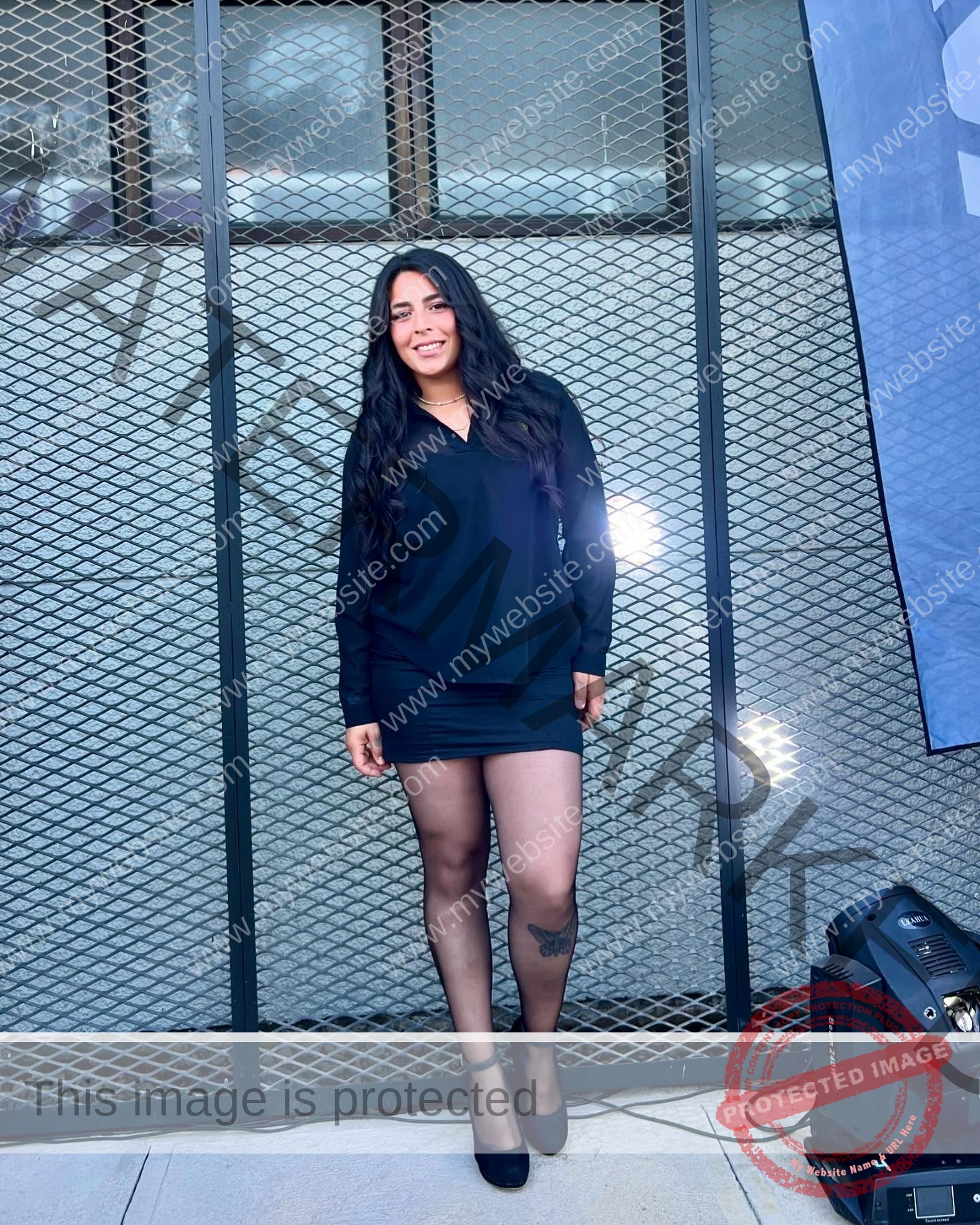 mariana walker-childe-marianawalker_-1845 Mariana Walker, hammer thrower from Chile, stands smiling in a black dress and heels before a metal fence with lights and blue banner.