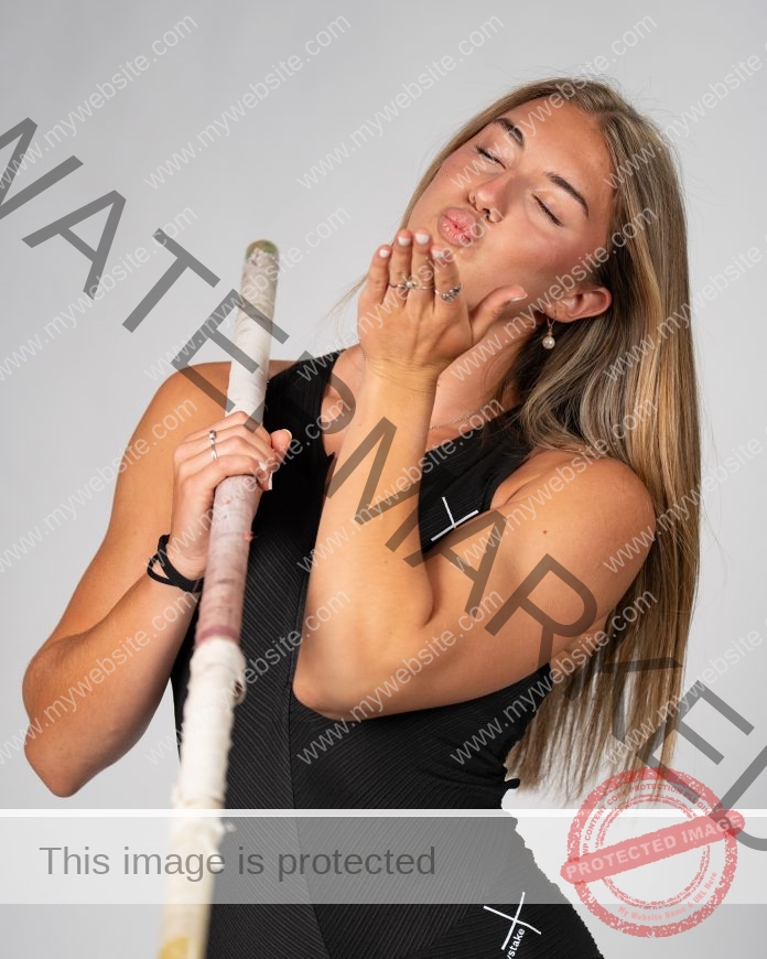 Nicole Krutilova A female pole vaulter from the Czech Republic with long blonde hair in black athletic gear holds a pole and blows a kiss.