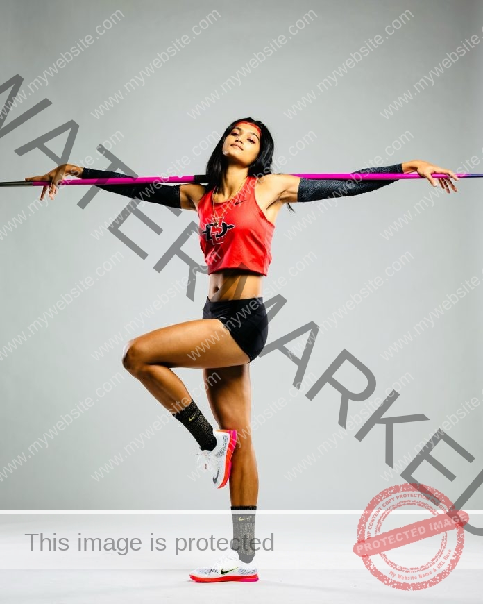 Pavana Nagaraj Oklahoma State track and field athlete Pavana Nagaraj poses on one leg, balancing a javelin across her shoulders in a studio.