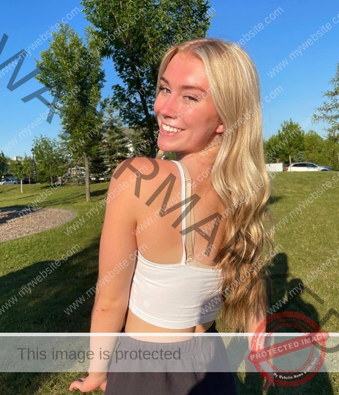 Rachel Grenke Rachel Grenke, a young woman with long blonde hair, smiles over her shoulder outdoors in Canada on a sunny day.