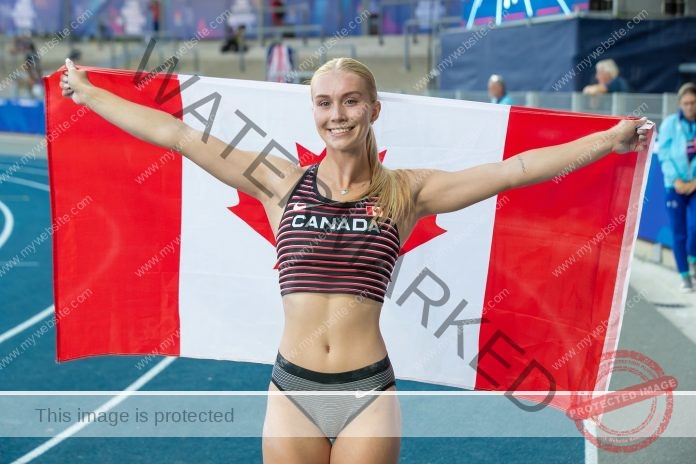 Rachel Grenke Rachel Grenke, a track and field athlete, smiles holding a Canadian flag on a blue track in Canada gear and shorts.