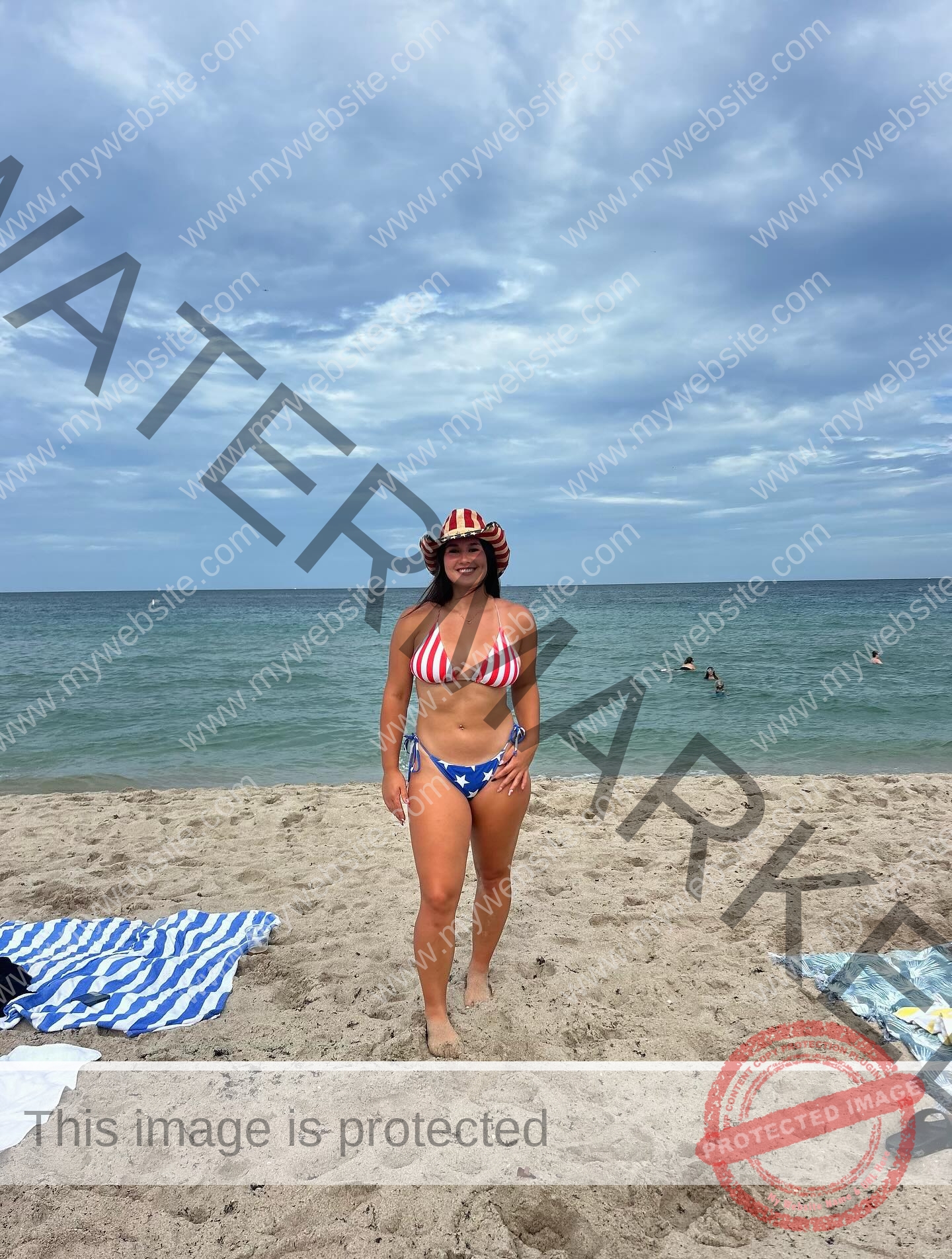 rosa-gergely-wake-forest-th-ro_gerg-08334 Rosa Gergely Rosa Gergely, in a stars and stripes bikini and cowboy hat, smiles on a sandy beach near towels under cloudy skies.