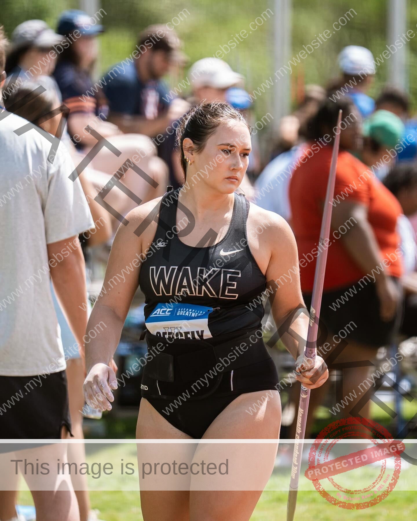 rosa-gergely-wake-forest-th-ro_gerg-2004 Rosa Gergely, javelin thrower from Wake Forest, holds a javelin at an outdoor track meet as spectators watch in the background.