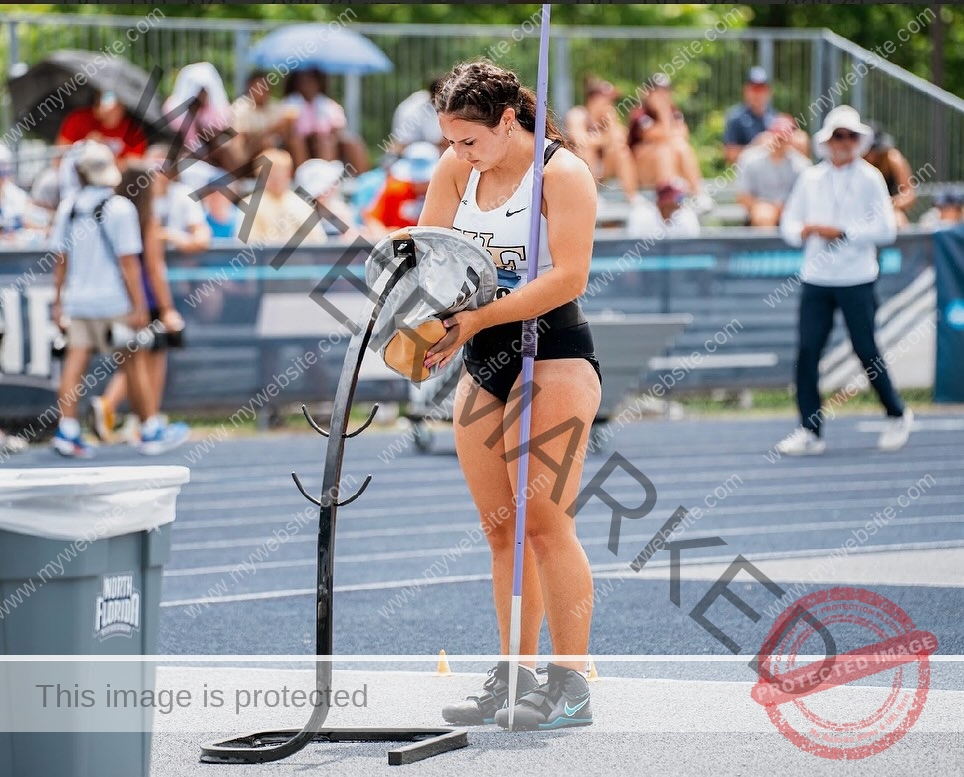 rosa-gergely-wake-forest-th-ro_gerg-2009 Rosa Gergely, javelin thrower from Wake Forest, stands on a track in sportswear with a javelin, handling a vest, at an outdoor event.