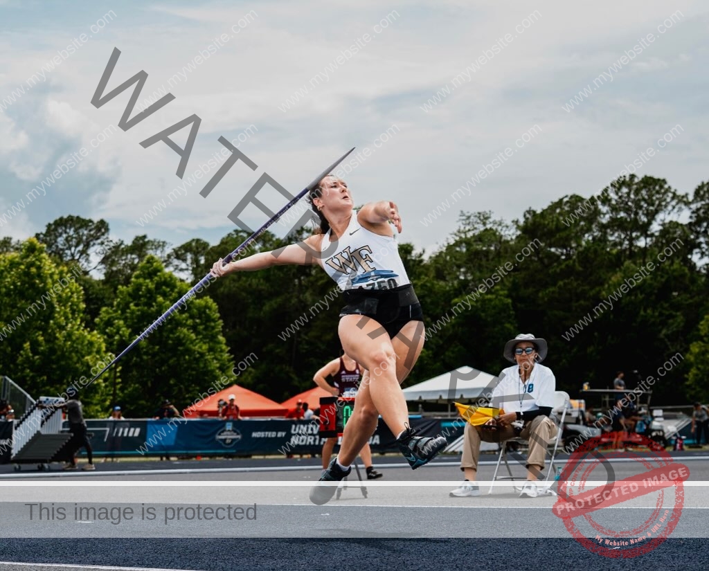 rosa-gergely-wake-forest-th-ro_gerg-2013 Rosa Gergely, javelin thrower from Wake Forest, in mid-motion prepares to throw a javelin on an outdoor track, trees and spectators behind.
