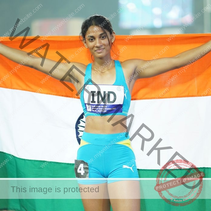 Sakshi Chavan Sakshi Chavan, a female track and field athlete in blue sportswear, proudly holds the Indian flag with arms outstretched, smiling in a race bib labeled IND 4.
