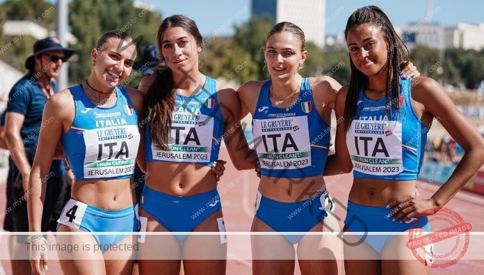 Sara Cirillo stands on the track in her track uniform, flanked by teammates with big smiles after winning a race.