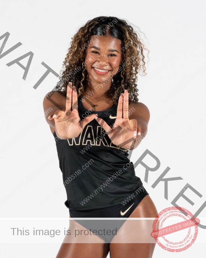 Savannahh Simmons, a smiling woman in a black Wake Forest track and field uniform, forms L and U with her fingers against a white background.