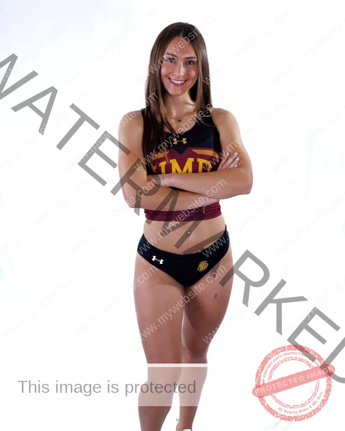 Sevanna Burke Simmons A young woman in athletic gear with IMD on her top stands confidently, arms crossed, smiling at the camera.