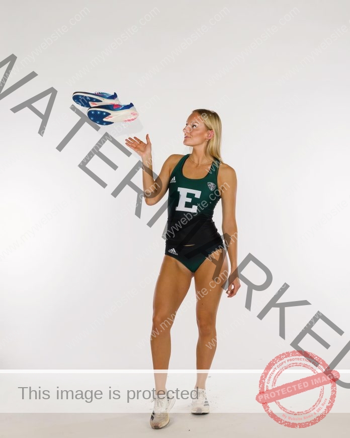 Sophie Emin posing ibn front of a white background, throwing her track shoes into the air.