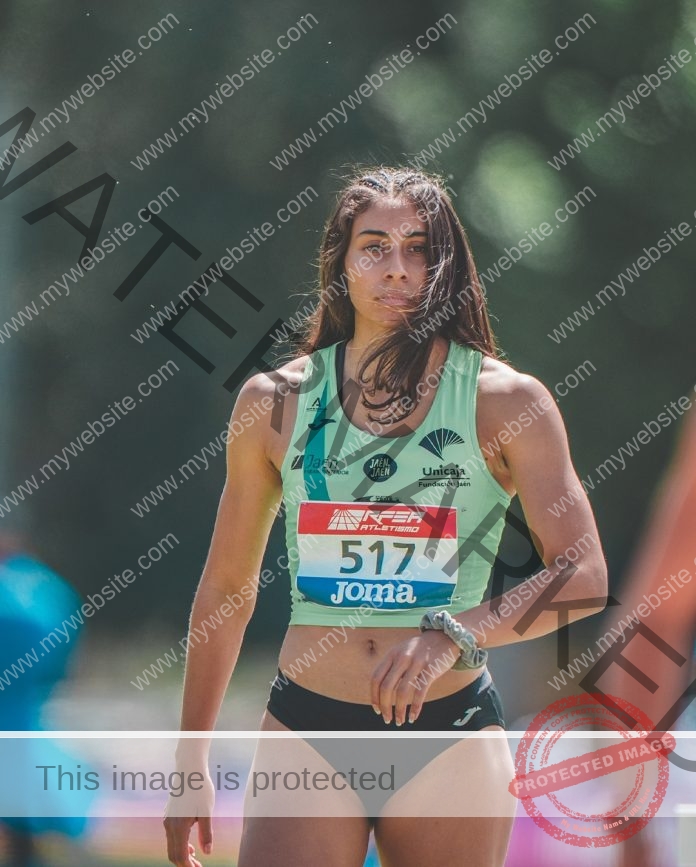 Wayra Romero A female athlete, Wayra Romero, in a light green top and black shorts outdoors, long brown hair, bib 517, at a Spain track event.