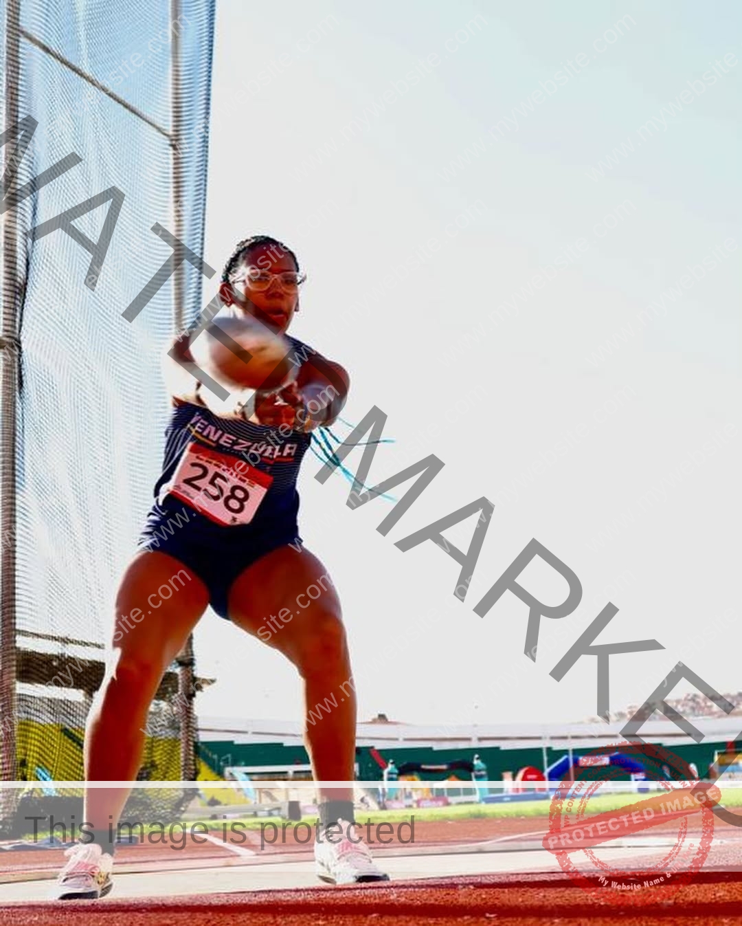 yenni-veroes-venezuela-yenni__throw-101 Alejandra Veroes, a female athlete in a Venezuela uniform with bib 258, gets ready to throw a hammer at an outdoor stadium.